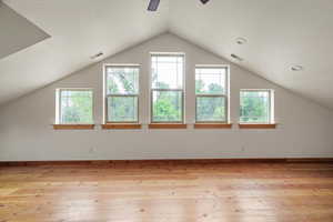 Bonus room featuring healthy amount of natural light, light wood-type flooring, a ceiling fan, and vaulted ceiling