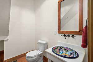 Half bathroom with toilet and wood finished floors