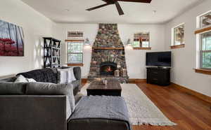 Living room with wood finished floors, a ceiling fan, and a fireplace