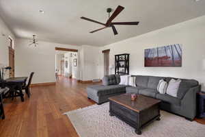 Living room with ceiling fan, hardwood / wood-style flooring, and a chandelier