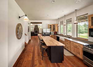 Kitchen with appliances with stainless steel finishes, butcher block countertops, a breakfast bar, glass insert cabinets, and a center island