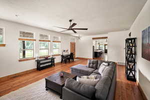 Living area with a ceiling fan and light wood-style flooring