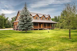 Log home with a porch, a front yard, and a metal roof