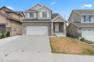Craftsman-style home featuring an attached garage, driveway, brick siding, a gate, and a front yard