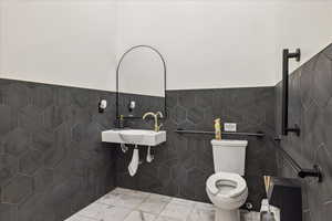 Bathroom with tile walls, a wainscoted wall, and marble finish flooring