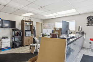 Miscellaneous room with wood finished floors, a drop ceiling, and a desk
