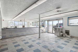 Basement with tile patterned floors, heating unit, and a textured ceiling