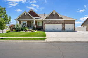Craftsman-style home featuring an attached garage, driveway, covered porch, and board and batten siding