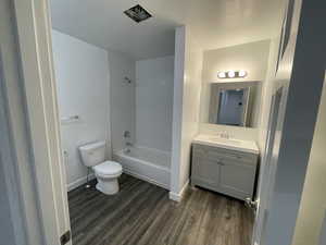 Bathroom featuring wood finished floors, vanity, and  shower combination