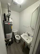 Half bathroom featuring water heater and wood finished floors