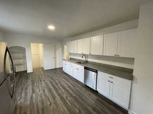 Kitchen featuring appliances with stainless steel finishes, dark countertops, dark wood-type flooring, white cabinetry, and recessed lighting