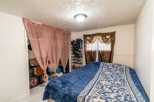 Bedroom with a textured ceiling and a wainscoted wall