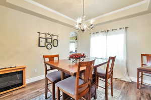 Dining room featuring arched walkways, crown molding, wood-type flooring, and a chandelier