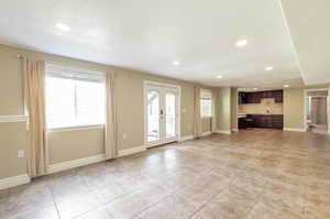 Unfurnished living room with recessed lighting, light tile patterned flooring, and french doors