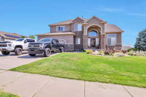 View of front of home featuring stucco siding, stone siding, concrete driveway, and a front yard