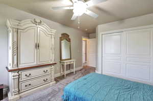 Bedroom featuring light carpet, a ceiling fan, and a closet