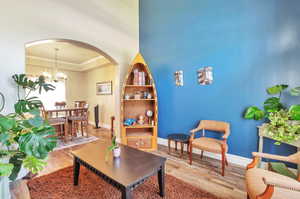 Living room featuring arched walkways, wood finished floors, a chandelier, and ornamental molding