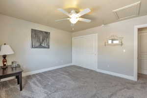 Unfurnished bedroom featuring carpet flooring, attic access, a closet, and ceiling fan