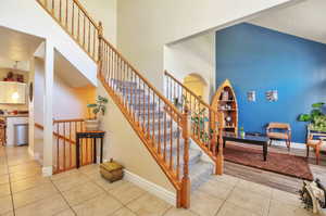 Staircase featuring tile patterned floors, a high ceiling, and arched walkways
