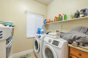 Washroom with washing machine and clothes dryer and light tile patterned floors