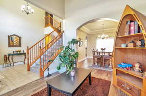 Living area with a chandelier, arched walkways, crown molding, wood finished floors, and stairway