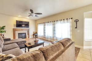 Living room featuring a ceiling fan, a tiled fireplace, and light wood finished floors