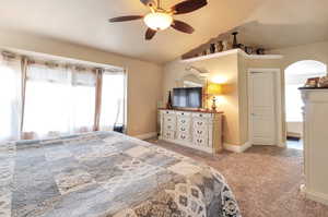 Carpeted bedroom featuring vaulted ceiling and ceiling fan
