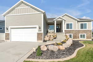 View of front of home featuring stone siding, board and batten siding, driveway, and roof with shingles