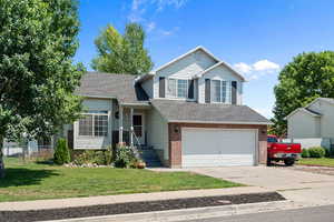 Tri-level home featuring an attached garage, concrete driveway, brick siding, and roof with shingles