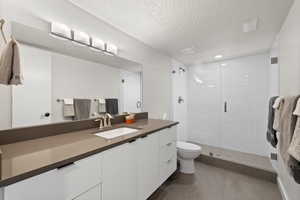 Bathroom with vanity, a stall shower, a textured ceiling, and tile patterned floors