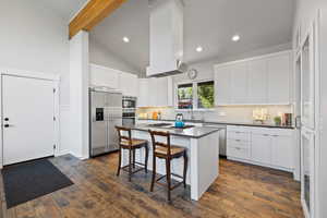 Kitchen with built in appliances, dark countertops, a breakfast bar area, backsplash, and a kitchen island