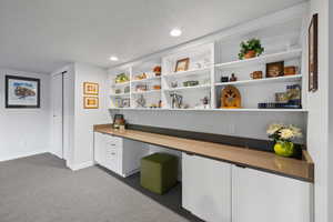 Office space with built in study area, a textured ceiling, dark carpet, and recessed lighting