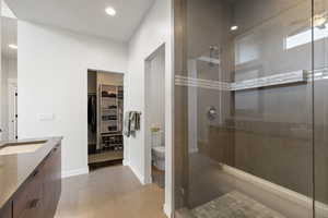 Full bath featuring a stall shower, double vanity, a walk in closet, and recessed lighting