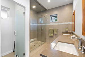 Full bath featuring a stall shower, double vanity, and recessed lighting