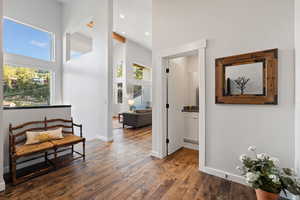 Corridor with healthy amount of natural light, dark wood-style floors, a towering ceiling, and recessed lighting