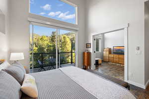 Bedroom with wood finished floors, a high ceiling, and access to exterior
