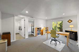 Carpeted office featuring a textured ceiling and recessed lighting