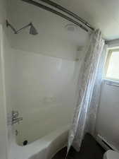 Bathroom with shower / bath combo and baseboard heating