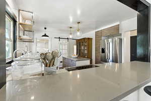 Kitchen with stainless steel fridge with ice dispenser, a barn door, plenty of natural light, and a center island