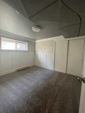 Unfurnished bedroom featuring a decorative wall, carpet, a wainscoted wall, and a closet