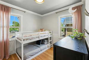 Bedroom with ornamental molding, multiple windows, and light wood-type flooring