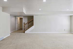 Carpeted empty room featuring recessed lighting and stairs
