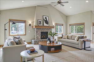 Living area featuring high vaulted ceiling, a ceiling fan, recessed lighting, a stone fireplace, and carpet flooring