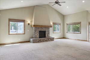 Unfurnished living room featuring high vaulted ceiling, carpet, ceiling fan, a stone fireplace, and recessed lighting