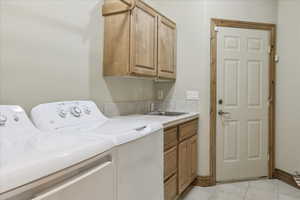 Washroom featuring cabinet space, washer and clothes dryer, and light tile patterned flooring