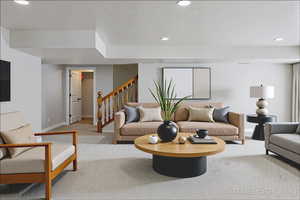 Carpeted living room with recessed lighting and stairs