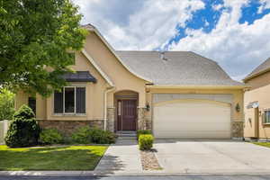 View of front facade with stone siding, a garage, stucco siding, and concrete driveway
