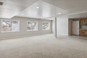 Unfurnished living room featuring light colored carpet, recessed lighting, and a textured ceiling