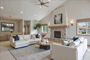 Carpeted living area featuring high vaulted ceiling, recessed lighting, a ceiling fan, and a fireplace