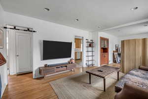 Living area featuring light wood-type flooring, recessed lighting, and a barn door